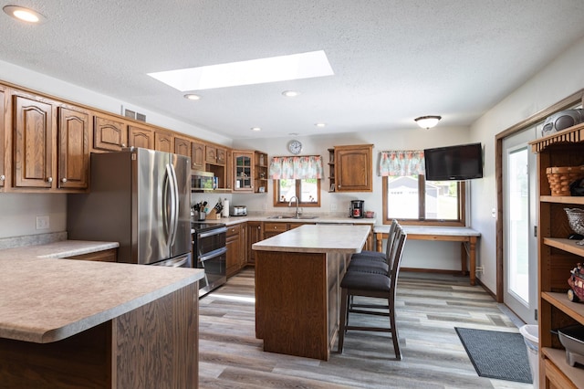 32 7th St, Buffalo City, WI 54622 - kitchen featuring stainless steel appliances, open shelves, a skylight, a breakfast bar area, and light countertops