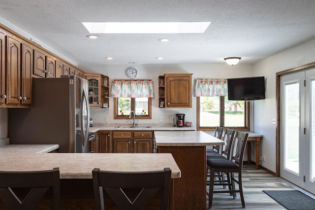 32 7th St, Buffalo City, WI 54622 - kitchen featuring freestanding refrigerator, a skylight, light countertops, a kitchen bar, and a textured ceiling