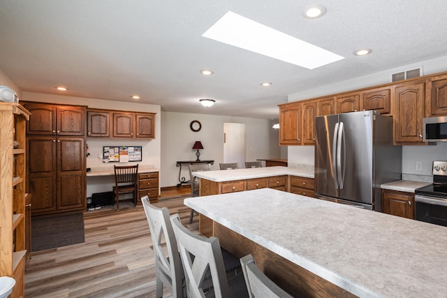 32 7th St, Buffalo City, WI 54622 - kitchen featuring stainless steel appliances, a skylight, a peninsula, light countertops, and light wood-style floors