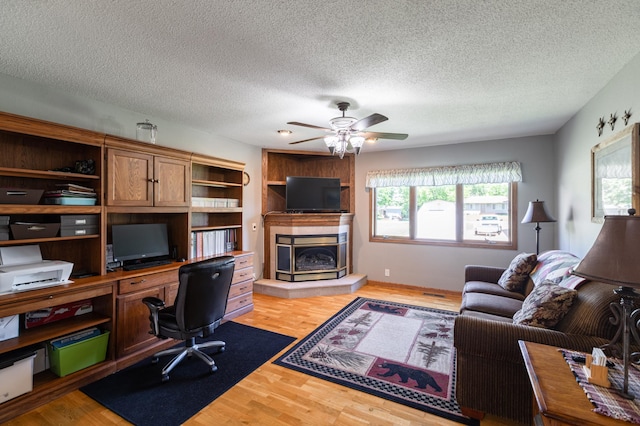 32 7th St, Buffalo City, WI 54622 - living area featuring a textured ceiling, a desk, ceiling fan, light wood-style floors, and a tile fireplace