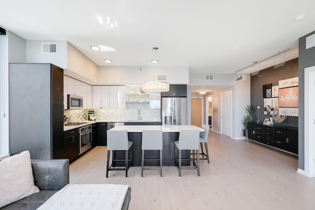 740 Portland Ave Unit 907, Minneapolis, MN 55415 - kitchen featuring appliances with stainless steel finishes, a sink, light countertops, a breakfast bar, and light wood finished floors