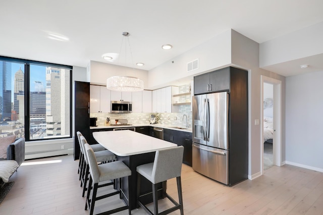 740 Portland Ave Unit 907, Minneapolis, MN 55415 - kitchen with appliances with stainless steel finishes, a sink, light wood finished floors, and a breakfast bar area