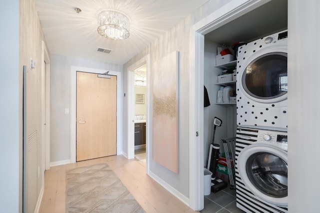 740 Portland Ave Unit 907, Minneapolis, MN 55415 - laundry room featuring estacked washer and dryer, a chandelier, baseboards, and wood finished floors
