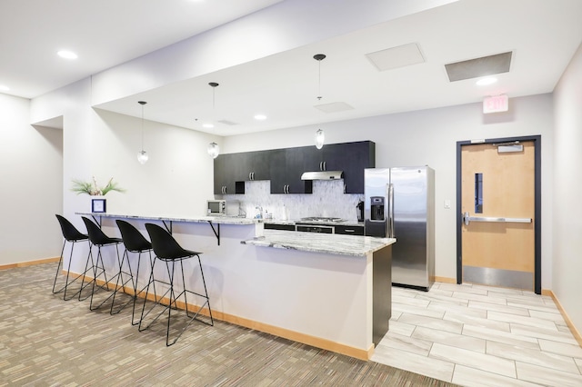 740 Portland Ave Unit 907, Minneapolis, MN 55415 - kitchen with appliances with stainless steel finishes, dark cabinetry, a breakfast bar, backsplash, and hanging light fixtures