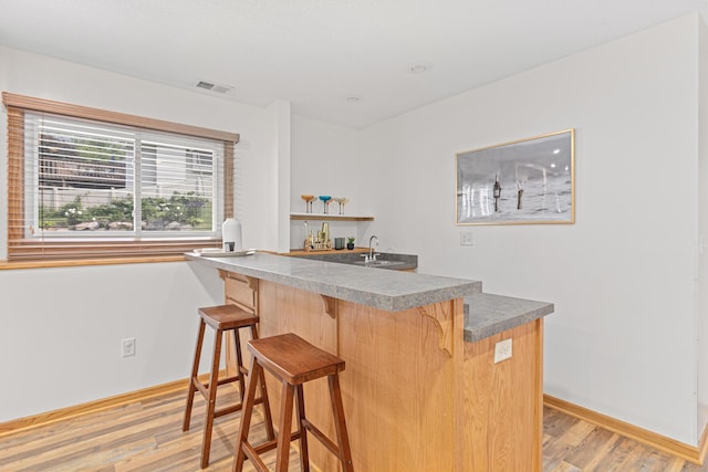 1112 Dakota St S, Shakopee, MN 55379 - kitchen with light wood-style floors, a kitchen bar, baseboards, a sink, and open shelves