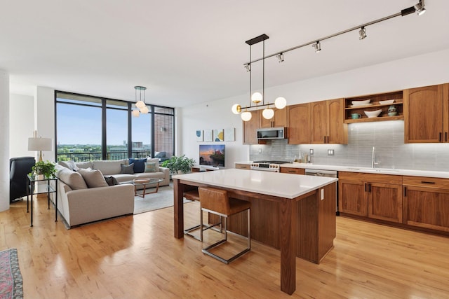 215 10th Ave S Unit 606, Minneapolis, MN 55415 - kitchen with appliances with stainless steel finishes, backsplash, light countertops, a center island, and a wall of windows
