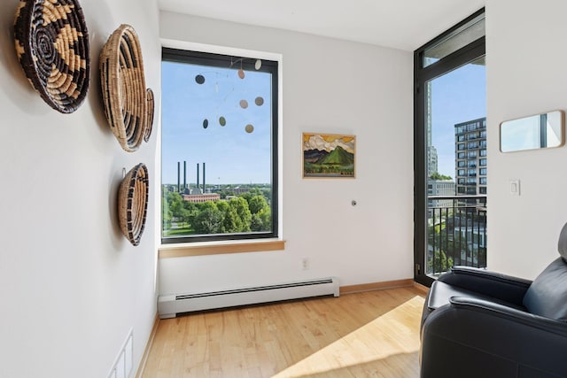215 10th Ave S Unit 606, Minneapolis, MN 55415 - living area featuring a baseboard radiator, healthy amount of natural light, wood finished floors, and a city view