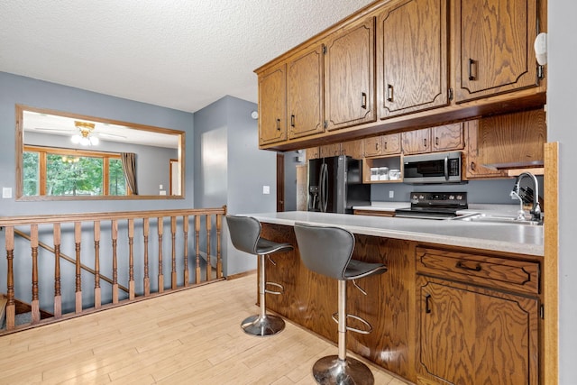 16724 Kenyon Cir NE, Ham Lake, MN 55304 - kitchen with stainless steel appliances, brown cabinets, wood finished floors, a peninsula, and light countertops
