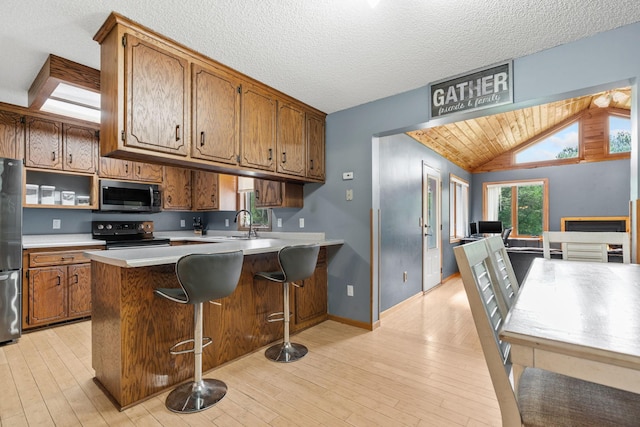 16724 Kenyon Cir NE, Ham Lake, MN 55304 - kitchen featuring stainless steel appliances, brown cabinets, light countertops, a peninsula, and light wood-style flooring
