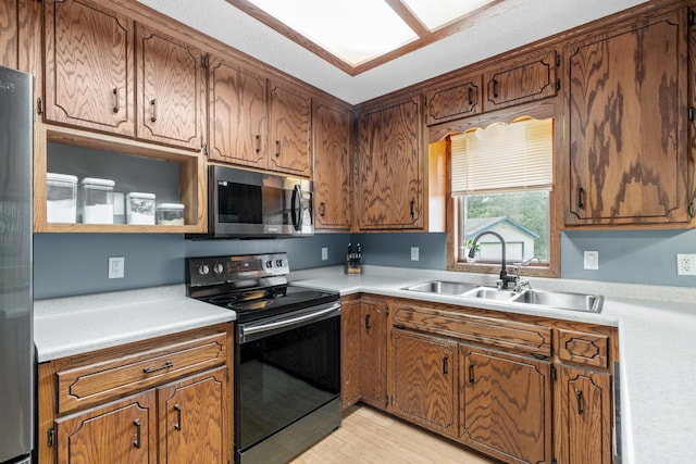 16724 Kenyon Cir NE, Ham Lake, MN 55304 - kitchen featuring black electric range, stainless steel microwave, light countertops, light wood-style flooring, and brown cabinetry
