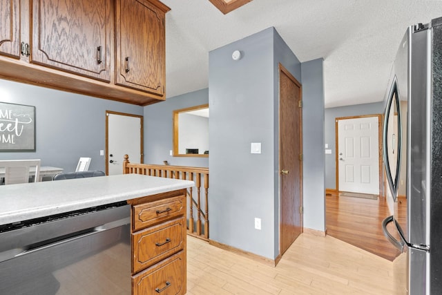 16724 Kenyon Cir NE, Ham Lake, MN 55304 - kitchen with appliances with stainless steel finishes, light wood finished floors, brown cabinetry, light countertops, and a textured ceiling