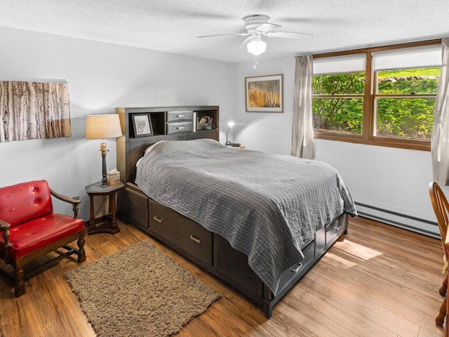 24810 96th St NW, Zimmerman, MN 55398 - bedroom featuring baseboard heating, light wood-style floors, a textured ceiling, and ceiling fan