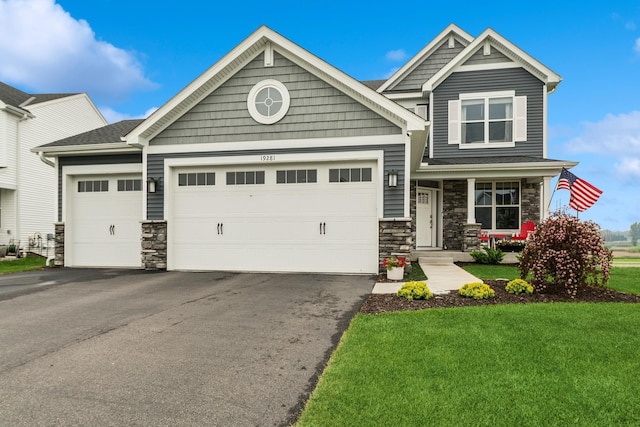 19281 Blue Stem Ct, Maple Grove, MN 55311 - craftsman-style home featuring stone siding, an attached garage, asphalt driveway, a front yard, and a porch
