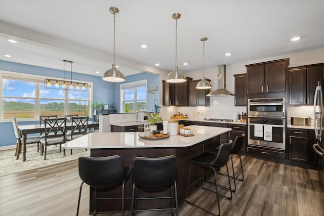 19281 Blue Stem Ct, Maple Grove, MN 55311 - kitchen featuring wall chimney range hood, stainless steel appliances, light countertops, tasteful backsplash, and dark wood-style flooring