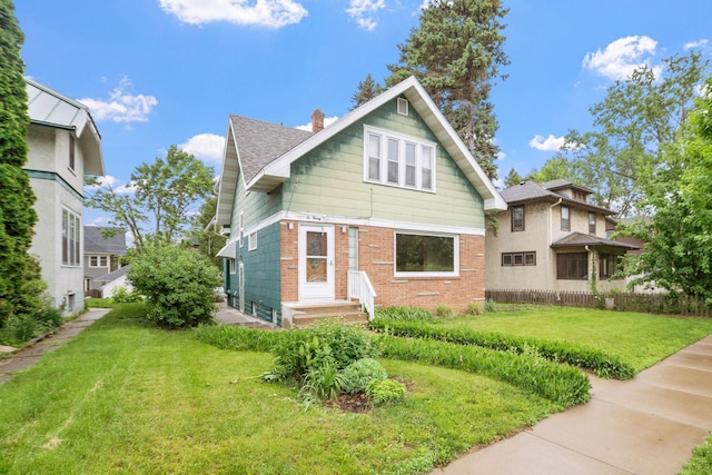 1027 Van Slyke Ave, Saint Paul, MN 55103 - view of front facade featuring a front yard, brick siding, a chimney, and a shingled roof