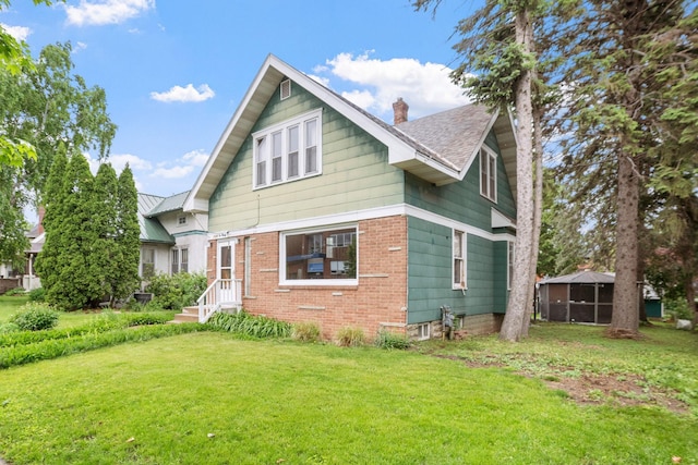 1027 Van Slyke Ave, Saint Paul, MN 55103 - view of front of home with a chimney, a front lawn, brick siding, and roof with shingles