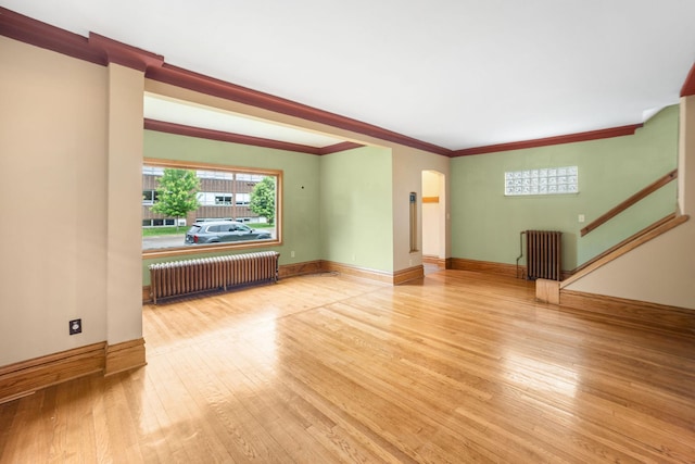 1027 Van Slyke Ave, Saint Paul, MN 55103 - unfurnished living room with radiator, hardwood / wood-style floors, arched walkways, baseboards, and ornamental molding