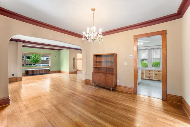 1027 Van Slyke Ave, Saint Paul, MN 55103 - unfurnished room featuring radiator heating unit, arched walkways, healthy amount of natural light, light wood-type flooring, and crown molding