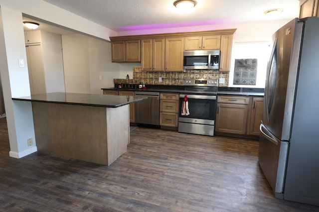 105 2nd St NE, New Prague, MN 56071 - kitchen with stainless steel appliances, dark countertops, dark wood finished floors, and tasteful backsplash