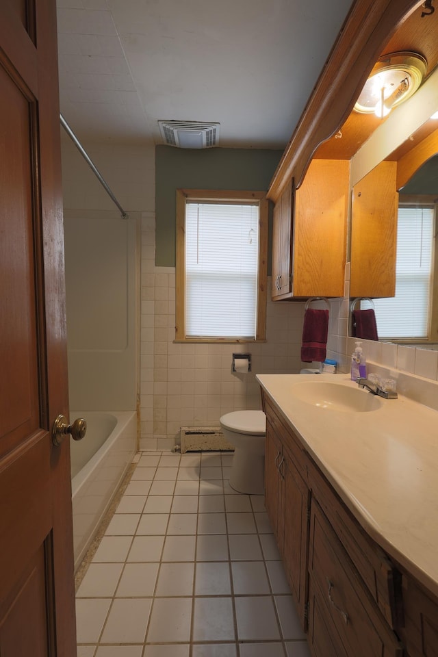 105 2nd St NE, New Prague, MN 56071 - bathroom featuring vanity, tile patterned floors, healthy amount of natural light, tile walls, and shower / tub combination