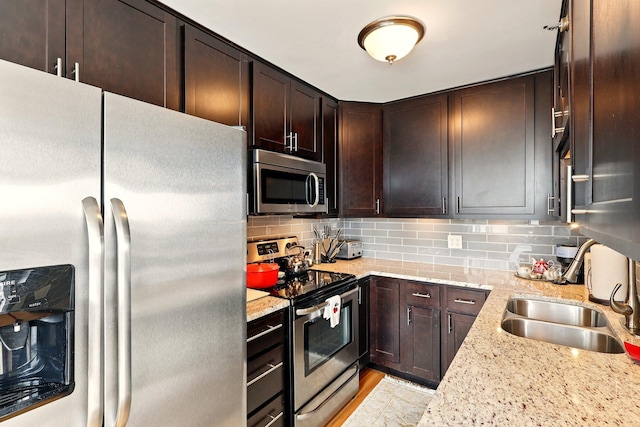 433 7th St Unit 1623, Minneapolis, MN 55415 - kitchen featuring appliances with stainless steel finishes, a sink, dark brown cabinetry, tasteful backsplash, and light stone counters