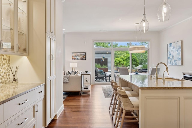935 Lake St E Unit 211, Wayzata, MN 55391 - kitchen with dark wood-style floors, light stone countertops, a kitchen breakfast bar, hanging light fixtures, and glass insert cabinets