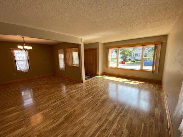 219 9th Ave SE, Rochester, MN 55904 - empty room with a chandelier, wood finished floors, a textured ceiling, and baseboards