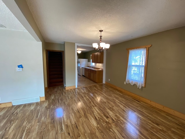 219 9th Ave SE, Rochester, MN 55904 - unfurnished dining area with a textured ceiling, a chandelier, baseboards, wood finished floors, and a sink