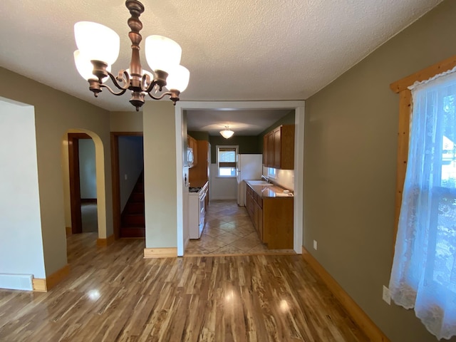 219 9th Ave SE, Rochester, MN 55904 - kitchen with arched walkways, a chandelier, light wood-style floors, a textured ceiling, and brown cabinetry