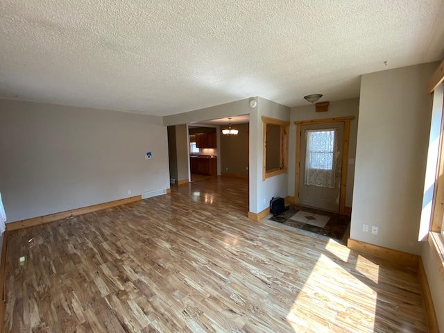 219 9th Ave SE, Rochester, MN 55904 - unfurnished living room featuring a textured ceiling, wood finished floors, a chandelier, and baseboards