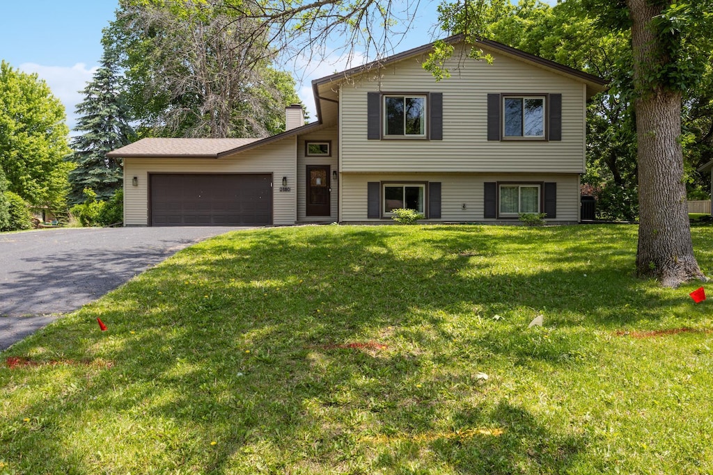 2880 Weston Ln N, Plymouth, MN 55447 - split level home with asphalt driveway, a garage, a chimney, and a front yard