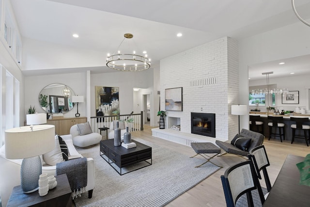 2324 Rivendell Ln, Minnetonka, MN 55305 - living room featuring a chandelier, light wood-style floors, a towering ceiling, a fireplace, and recessed lighting