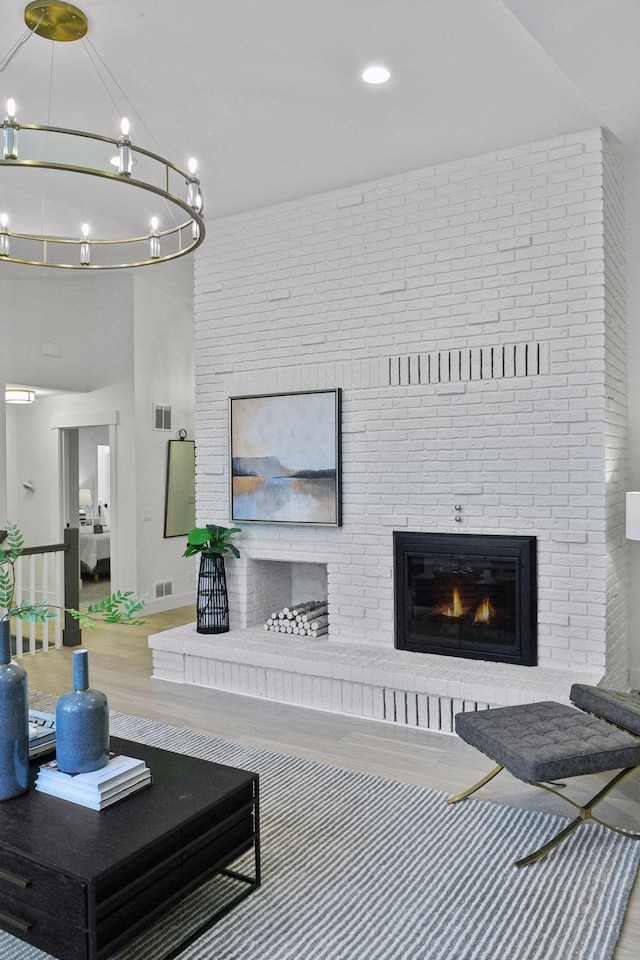 2324 Rivendell Ln, Minnetonka, MN 55305 - living room with a brick fireplace, wood finished floors, and a chandelier