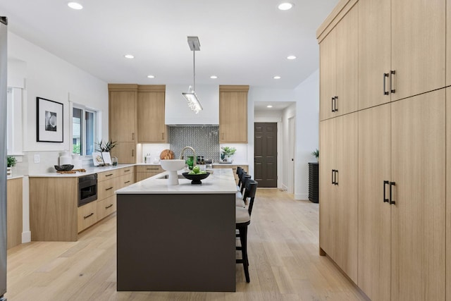 2324 Rivendell Ln, Minnetonka, MN 55305 - kitchen featuring light brown cabinetry, a kitchen island, modern cabinets, tasteful backsplash, and recessed lighting