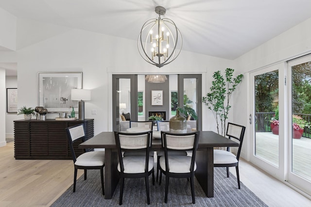 2324 Rivendell Ln, Minnetonka, MN 55305 - dining space featuring vaulted ceiling, light wood-type flooring, a chandelier, and a lit fireplace