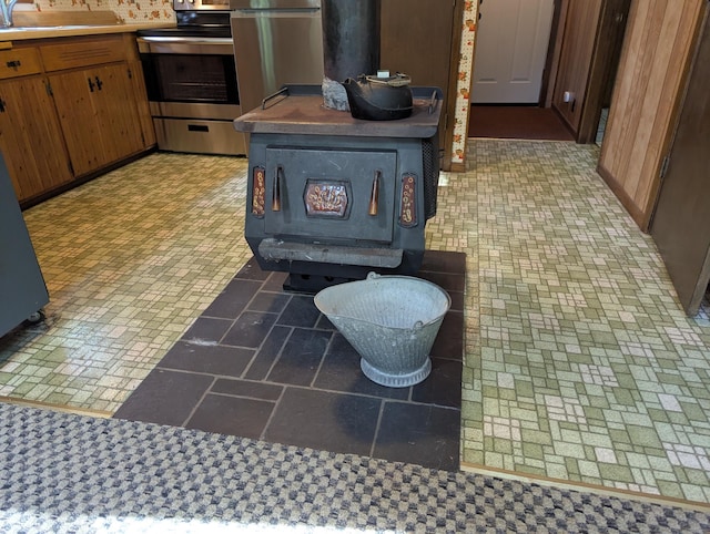 24863 Norway Pine Pl, Ross Lake Twp, MN 56447 - kitchen with a wood stove, electric range, a sink, brown cabinets, and brick patterned floors
