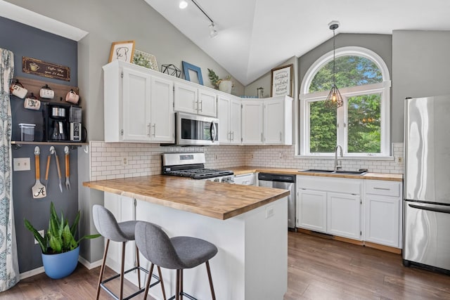 903 6th Ave NW, Buffalo, MN 55313 - kitchen featuring stainless steel appliances, lofted ceiling, wooden counters, a peninsula, and white cabinets