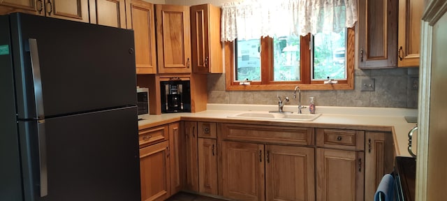 12183 Crooked Lake Ln SW, Moe Twp, MN 56327 - kitchen with freestanding refrigerator, a sink, light countertops, brown cabinets, and backsplash