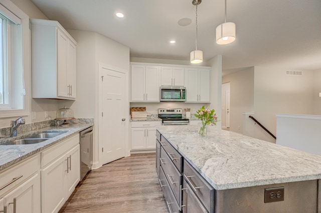 1345 Bluff Border Rd, New Richmond, WI 54017 - kitchen featuring appliances with stainless steel finishes, a sink, light wood finished floors, white cabinetry, and a center island
