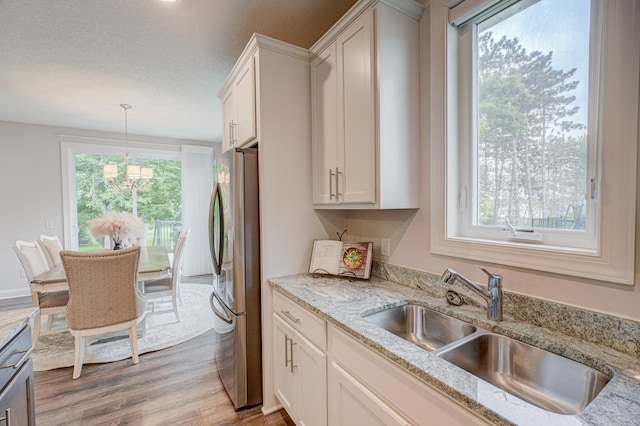 1345 Bluff Border Rd, New Richmond, WI 54017 - kitchen with freestanding refrigerator, a sink, light wood-type flooring, pendant lighting, and light stone counters