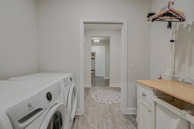 1345 Bluff Border Rd, New Richmond, WI 54017 - washroom featuring washer and clothes dryer, cabinet space, baseboards, and light wood-style flooring