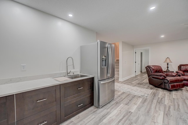 1345 Bluff Border Rd, New Richmond, WI 54017 - kitchen with stainless steel fridge, a sink, dark brown cabinetry, light wood-type flooring, and light countertops