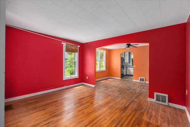 543 Pearl St, River Falls, WI 54022 - unfurnished room with wood finished floors, arched walkways, baseboards, and a ceiling fan