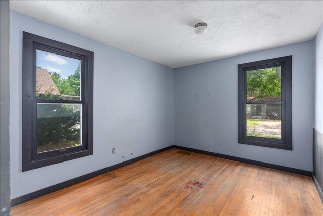 543 Pearl St, River Falls, WI 54022 - spare room with wood finished floors, baseboards, and a textured ceiling