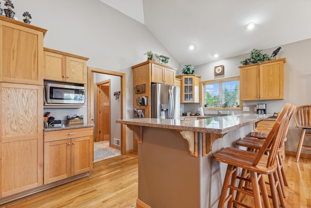 26033 607th St, Mantorville, MN 55955 - kitchen with stainless steel appliances, a kitchen bar, light wood finished floors, glass insert cabinets, and light stone counters