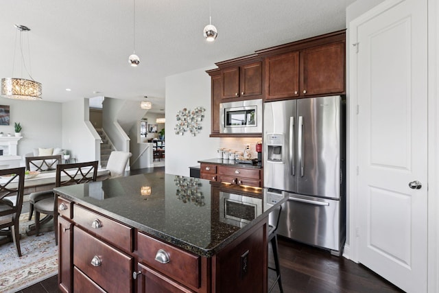 3751 Crane Island Ct, Minnetrista, MN 55331 - kitchen featuring stainless steel appliances, dark wood finished floors, hanging light fixtures, a center island, and a breakfast bar