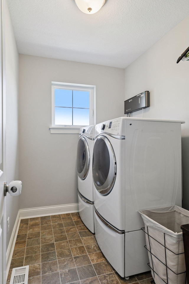 3751 Crane Island Ct, Minnetrista, MN 55331 - washroom with washing machine and dryer, baseboards, a textured ceiling, and dark stone finish flooring