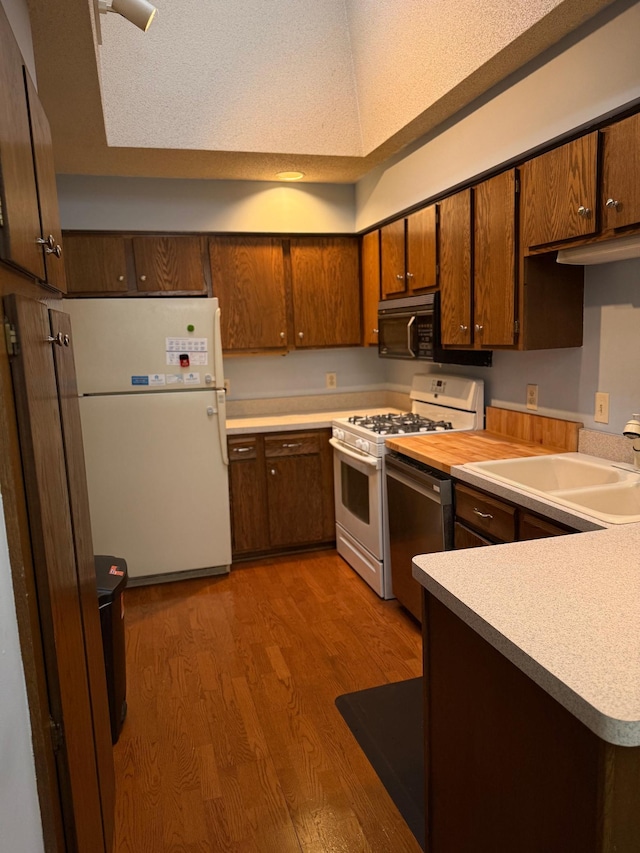 14410 92nd Ave N, Maple Grove, MN 55369 - kitchen with white appliances, a sink, wood finished floors, light countertops, and a peninsula