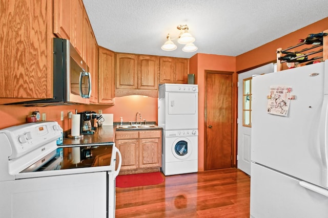 3865 Wahtomin Trl NW, Alexandria, MN 56308 - kitchen with white appliances, stacked washing machine and dryer, wood finished floors, a sink, and a textured ceiling
