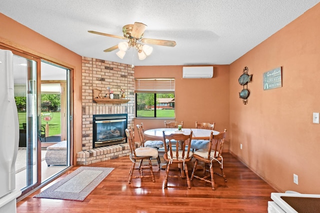 3865 Wahtomin Trl NW, Alexandria, MN 56308 - dining room featuring a wall mounted AC, ceiling fan, wood finished floors, a textured ceiling, and a fireplace
